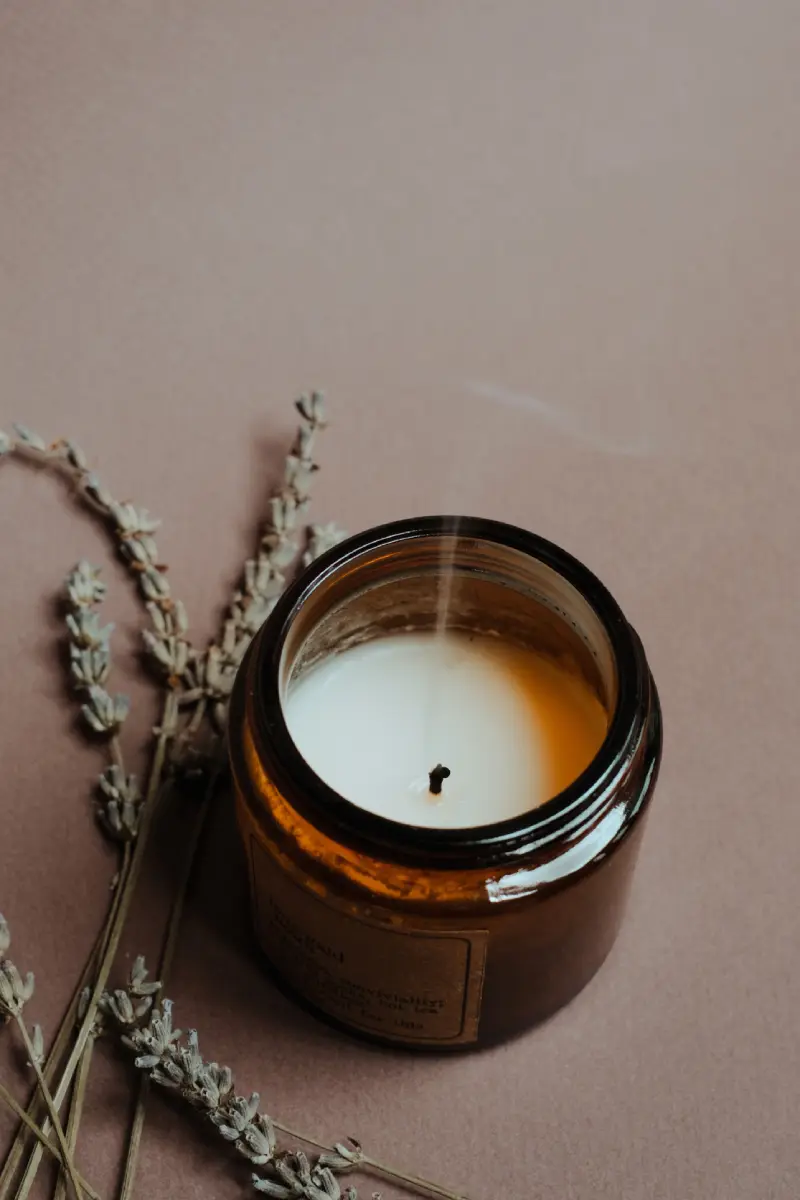 A lit Ayurvedic candle beside dried lavender