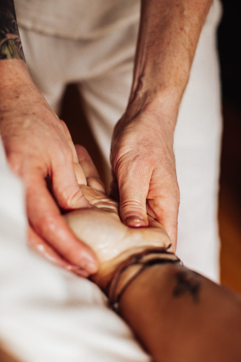 Oiled hands massaging a client's hand